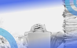 A person covering their head surrounded by files. Data overload is one challenge vertical SaaS companies must overcome.