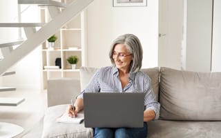 A woman sitting on a couch with a laptop resting on her lap.