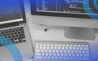 A laptop, keyboard, and desktop displaying code