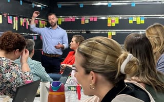 Jon Pinney leads a meeting in front of a wall of Post-It notes.