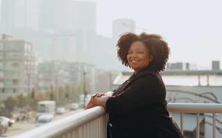 Portrait of Jackie Ivy-Hardin standing on a balcony overlooking a city street.