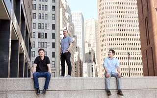 Three NS1 leaders on top of concrete wall amid cityscape background