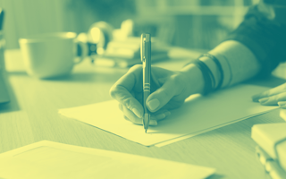 A hand holding a pen to an empty page.