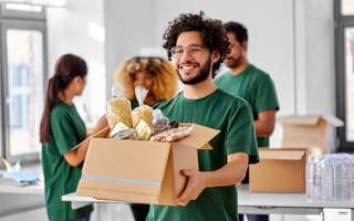 A volunteer carries a box filled with food donations.