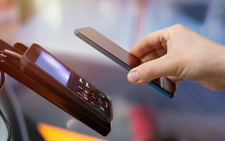 Someone holds a phone over a payment system.