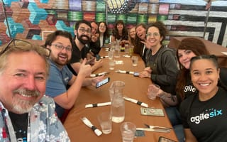 Selfie of Agile Six team members sit at a long dining table together