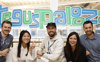Group photo of five Tegus team members in front of sign reading “Teguspalooza.”
