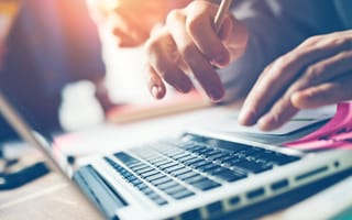 A close up of two hands typing on a laptop keyboard.