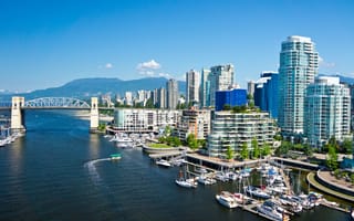 A view of the Vancouver skyline that includes several tall buildings and a bridge over the water.