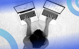 A woman typing on two laptops at once.