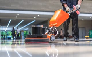 A person cleans a floor with a machine.