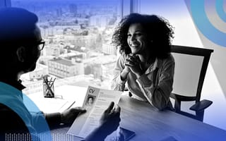 A man interviewing a woman in an office high-rise.