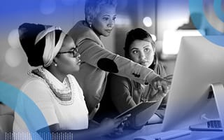 Three women working on a computer and tablet together.