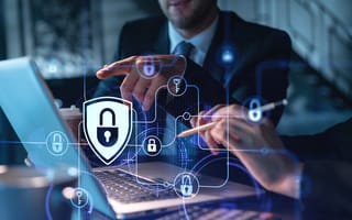 Two colleagues working together to protect clients confidential information and cyber security. IT hologram padlock icons modern office background at night time.