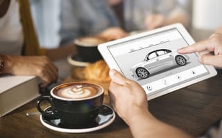 two hands holding a tablet and examining a car-buying interface.