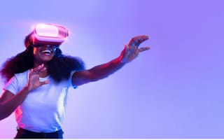 Excited young lady using VR glasses, touching something invisible, experiencing a virtual reality adventure on neon studio background.