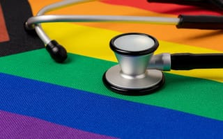 A doctor's stethoscope sits on top of the progress pride flag.