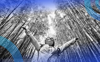 A woman spreads her arms in a forest