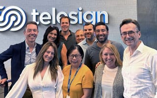 A group of Telesign employees stand together in front of the company sign.