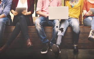 College students are pictured sitting with laptops and books.