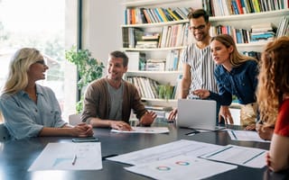 A group of business professionals are gathered around a conference table.