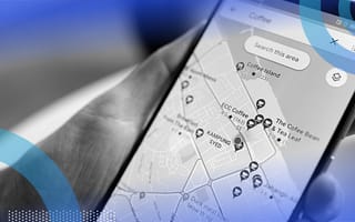A hand holding a phone showing a Google Maps search for “coffee.”
