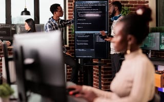 Engineers reviewing code on a monitor in the office