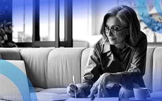 An older woman takes notes while looking at a laptop with a cup of tea