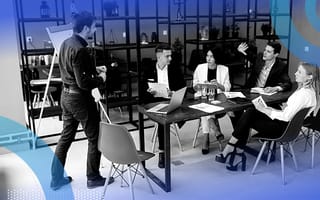 Employees at a table listening to a training presentation.