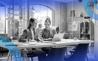 Two women work at a laptop in a loft space