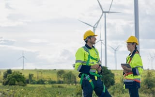 Two workers stand in front of windmills.
