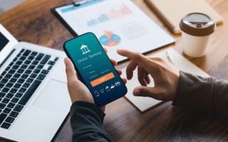 A close up of a pair of hands holding a smartphone with the login page for a digital banking app displayed on the phone screen.