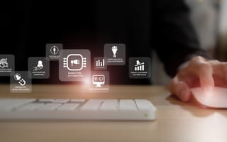 Image of a person using a mouse and keyboard with a graphic overlay of icons conveying the concept of marketing automation.