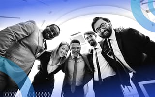 A group of happy young workers huddle and look into the camera, smiling