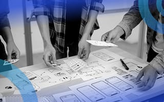 Three people captured from the elbow down putting together wireframes of a product on paper.