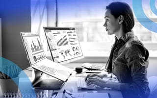 A business analyst looking at charts on a desktop computer.