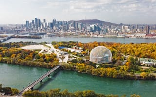 An aerial view of Montreal in the autumn. The Montreal biosphere is present in the foreground and the skyline is in the background.