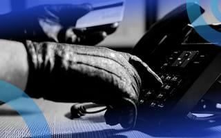 A close-up of someone’s gloved hand dialing on a landline phone while the other gloved hand is holding a credit card.