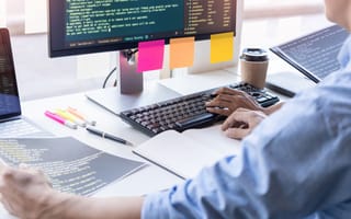 Software developer writing code and looking at notes.