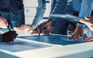 Group of engineers studies a construction blueprint.
