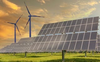 Image of a solar panel and wind turbine in a grass field.