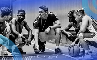 An adult coach crouched with four teenage basketball players in discussion on a basketball court.
