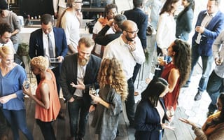 A gathering of people at a networking event is shown.