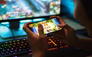 A close up of a pair of hands holding a smartphone and playing a mobile game.