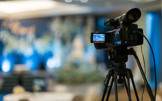 A video camera sits on a tripod.