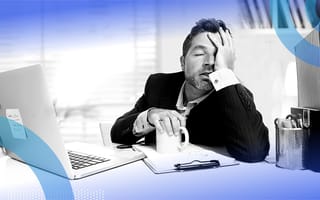 A stressed-out manager sitting at a desk with a computer and a coffee cup.