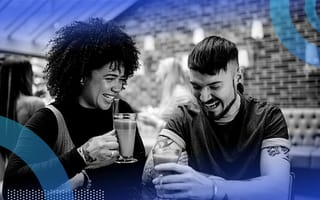 Two friends laughing together at a bar.