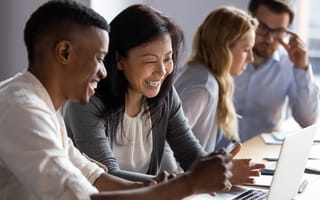 Four people looking at work together, smiling and discussing.
