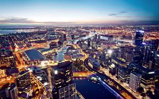 An aerial view of the Melbourne skyline with several buildings lit up at sunset.