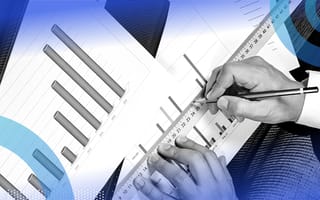 A close-up of a business man’s hand measuring with a ruler and pen on a paper bar graph.